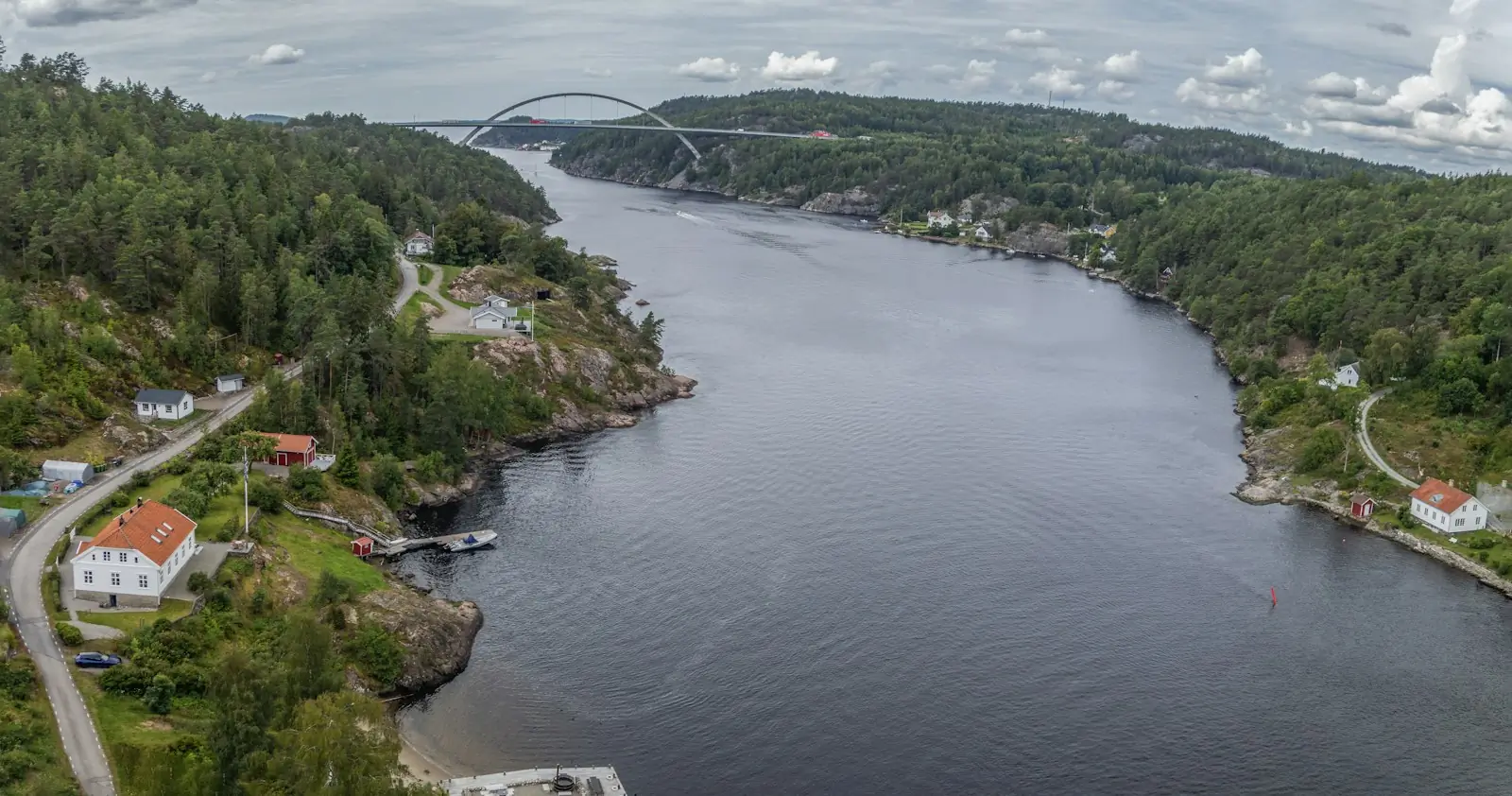 Svinesundsbrua over Iddefjorden sett ovenfra, med skog og hus langs fjorden